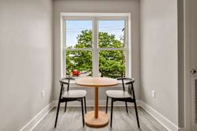 A small table with two chairs in front of a window.