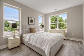 A bedroom with a large bed and a window overlooking a parking lot.