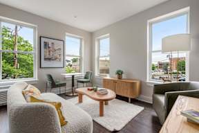 A living room with a grey couch, a green chair, a wooden coffee table, and a framed picture on the wall.