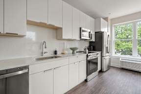 A modern kitchen with white cabinets and stainless steel appliances.