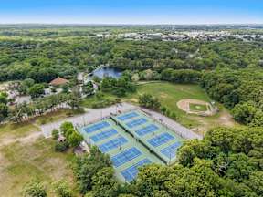 A large solar panel array is surrounded by trees and a baseball field.