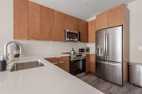 A modern kitchen with a stainless steel refrigerator and wooden cabinets.