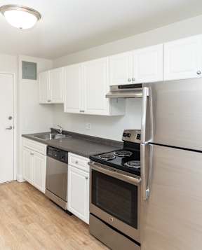 Adams Village apartments view of white kitchen with stainless appliances