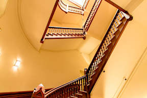 A staircase with a wooden handrail and a light on the wall.