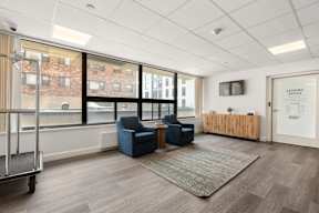 A leasing office is located in a modern office space with blue chairs and a wooden reception desk.