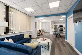 A blue couch with a yellow pillow sits in a room with a white ceiling.