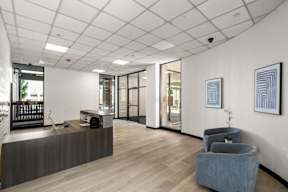 A reception area with a grey sofa and a wooden desk.