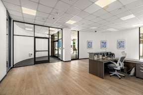 A modern office with a wooden floor and white walls.