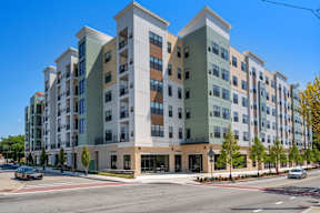 A modern apartment building with cars parked in front.