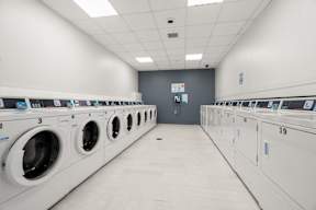 A row of washing machines are lined up in a laundromat.