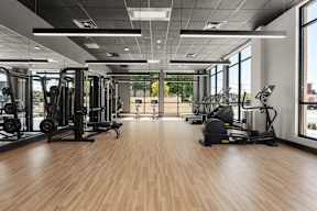 A gym with a variety of equipment including treadmills, weights, and exercise machines.