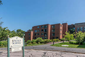 Exterior of lincoln school apartments with greenery and signage