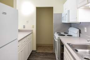 an empty kitchen with white cabinets and a white stove and refrigerator, apartment intererior