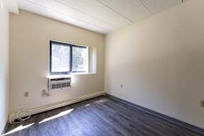 an empty bedroom of lincoln school room with white walls and vinyl flooring and A/C unit