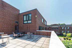 a patio with tables and chairs in front of a brick building, rooftop deck