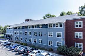 A parking lot with cars and a building with a red brick section.