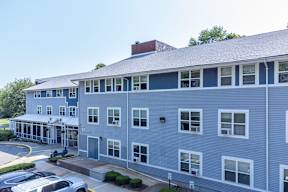 A large grey building with a lot of windows and a covered walkway.