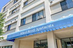 A building with a blue awning that says School Street Apartments.