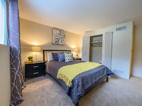 A bedroom with a bed, nightstands, and a painting on the wall.