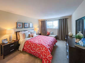 A bedroom with a red bedspread and a large bed.