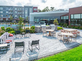 a patio with tables and chairs and a pool in the background