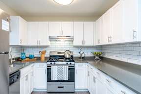 a white kitchen with stainless steel appliances and white cabinets