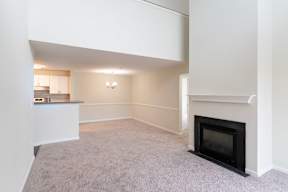 The Loft living room with a fireplace and grey carpet at Ledges Apartments in Weymouth.