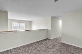 Upstairs room with a carpeted floor and a window in the Ledges Apartments.