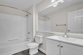 A white bathroom with a toilet, sink, and bathtub at the Ledges Apartments in Weymouth.