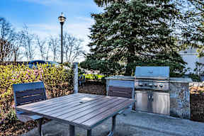 A picnic table is in front of a grill at the Ledges Apartments.