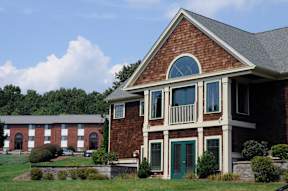 A red brick house with a green door and windows.