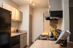 A black refrigerator is in a kitchen with a wooden counter.