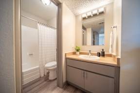 A bathroom with a toilet, sink, and mirror.