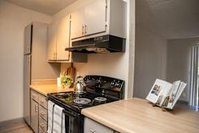 A kitchen with a black stove top oven and white cabinets.