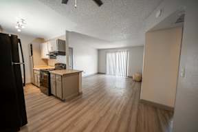 A kitchen with wooden floors and a black refrigerator.