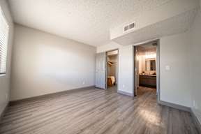 A room with a wooden floor and a doorway leading to another room.
