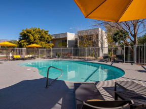 a swimming pool with yellow umbrellas and a building in the background
