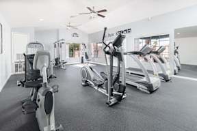 A gym with a row of treadmills and elliptical machines.