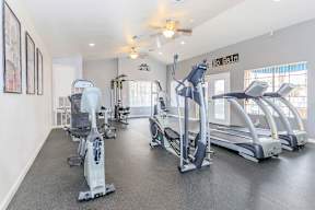 A gym with a variety of exercise equipment including treadmills, elliptical machines, and stationary bikes.