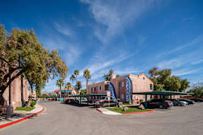 A parking lot with a building and palm trees in the background.