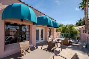 A patio with tables and chairs under blue awnings.