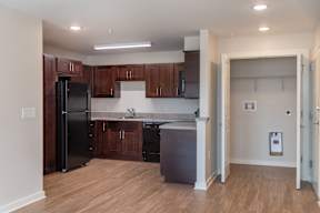 A kitchen with wooden cabinets and a black refrigerator.