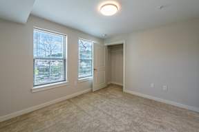 A room with a carpeted floor, a window with blinds, and a door.