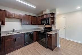 A kitchen with dark wood cabinets and black appliances.