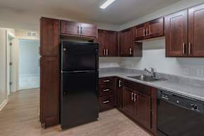 A kitchen with a black refrigerator and wooden cabinets.