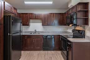 A kitchen with dark wood cabinets and black appliances.