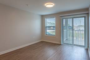A room with a sliding glass door leading to a balcony.