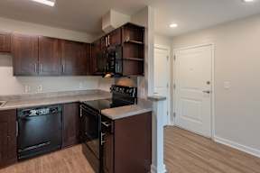 A kitchen with brown cabinets and black appliances.