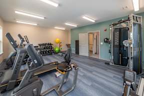 A gym with a blue carpet and a variety of exercise equipment.
