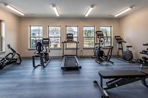 A gym with a variety of equipment including treadmills, stationary bikes, and weight machines.